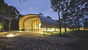 The structural steel bracing is integrated with the upturned hull-like roof, which is clad with LYSAGHT CUSTOM ORB® profile made from COLORBOND® Ultra Steel in the colour Dune®.