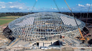 Curved light steel purlins made from GALVASPAN® steel create the Velodrome's distinctive shell-shaped roof structure. It is covered by ZINCALUME® zinc/aluminium alloy coated steel rollformed into Lysaght LONGLINE 305 sheeting in specifically tapered lengths of more than 24 metres.